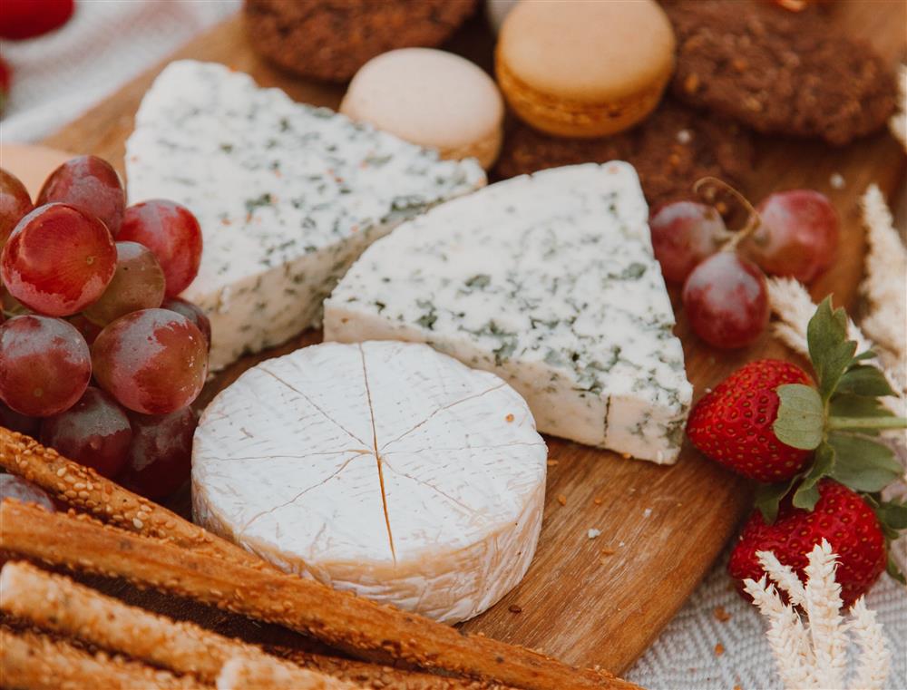 A serving tray containing cheese slices, fruit and other snacks